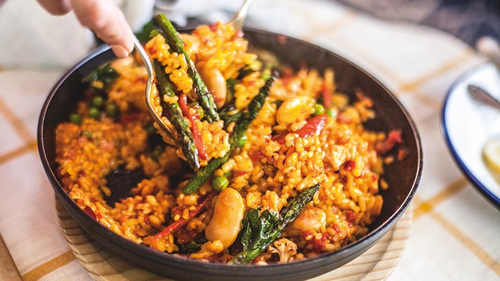 A person serving paella from a metal dish